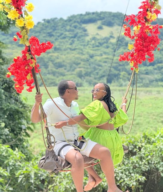 Brian and Angella on a flower-covered swing above green hills